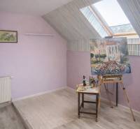 Attic studio with paintings in a family house, floor with wooden decor.