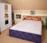 Bedroom in a family house with a bed, white wardrobe, and wall decorations.