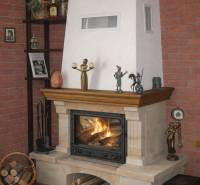 Fireplace in a family house, surrounded by a brick wall with decorative figurines and a basket of wood.