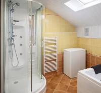 A bathroom in a family house with a corner shower, bathtub, and washing machine.