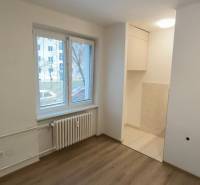 Studio apartment with a window, radiator, and floor with wood decor.