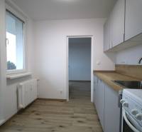 A kitchen in a 3-room apartment with a wooden decor floor, white cabinet, and stove.