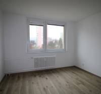 A room in a three-room apartment with a wooden decor floor and white walls.