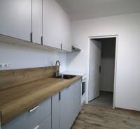 A kitchen in a 3-room apartment with a wooden decor floor and a functional wooden counter.