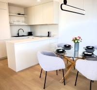 A kitchen in a 3-room apartment with a wooden decor floor, dining table, and chairs.