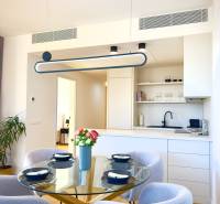 Dining room in a 3-room apartment with a wood-patterned floor and a glass table.