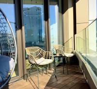 Balcony in a 3-room apartment with wicker chairs and a floor with a wooden decor.