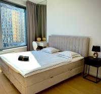 Bedroom with a bed and a table in a 3-room apartment with a wooden decor floor.