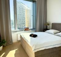 A bedroom with a large window, curtains, and a wooden decor floor in a 3-room apartment.