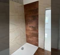A bathroom in a family house with ceramic tiles and a shower enclosure.