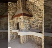 A fireplace with stone cladding in a family house, decorated with brick details.