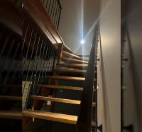 A staircase with a railing leads to the upper floor in a family house, with a wooden decor floor.