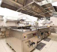 Professional kitchen with stainless steel equipment, large hoods, and tiled floors in commercial premises.