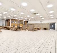 A large room with white tiles, tables, and chairs in a commercial space.