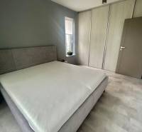 Bedroom with a bed and built-in wardrobe in a 2-room apartment, floor with wooden decor.