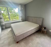 A bedroom in a two-room apartment with a large window and a comfortable bed.