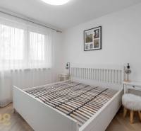 A bedroom with a white bed, nightstands, and a wooden decor floor in a 3-room apartment.