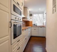 A kitchen in a 3-room apartment with white cabinets and a wooden decor floor.
