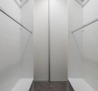 A wardrobe in a 3-room apartment with white shelves and a gray carpet.