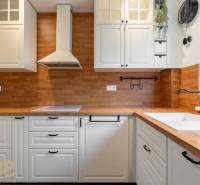 A kitchen in a 3-room apartment with a wooden decor floor and white cabinets.