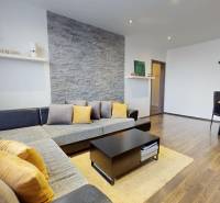 Living room in a 4-room apartment with a sofa, dining table, and wooden decor flooring.