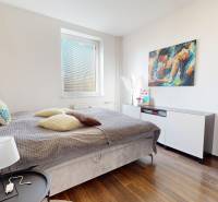 Bedroom in a 4-room apartment with a bed, nightstand, and wooden decor flooring.