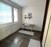 A room with a table and a shelf in a 4-room apartment with a wooden decor floor.