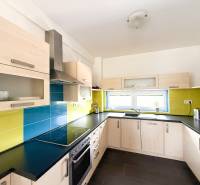 The kitchen of a 2-room apartment with colorful tiles and light cabinets.