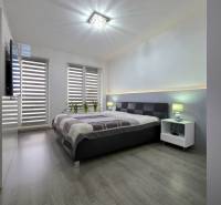 Bedroom in a 3-room apartment with wood-patterned flooring and a large bed.