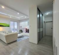 Living room in a 3-room apartment with a wooden decor floor and a light-colored sofa set.