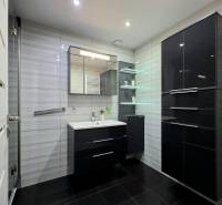 A bathroom in a 3-room apartment with cabinets and a mirror in black decor.