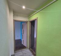 Hallway of a 3-room apartment with ceramic tiles and colorful walls, open doors to the rooms.
