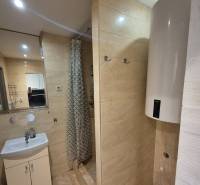 Bathroom in a 3-room apartment with beige tiles, a shower corner, and a sink.
