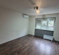 A room in a 3-room apartment with a wooden decor floor and a large window.