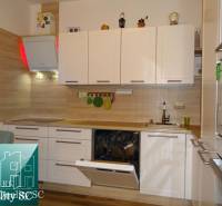 A kitchen unit with white cabinets and a floor with a wooden decor in a 2-room apartment.