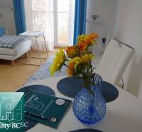 Interior of a 1-room apartment with flowers in a vase on the table and a sofa.