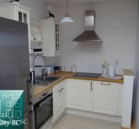 A kitchen in a studio apartment with white cabinets and stainless steel appliances.