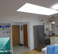 A kitchen in a studio apartment with decorative shelves and a wooden-patterned floor.