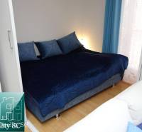 A bedroom in a one-room apartment with a large bed and a floor with a wooden decor.