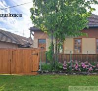 A family house in Horné Lefantovce with a wooden gate, a tree, and blooming hydrangeas.