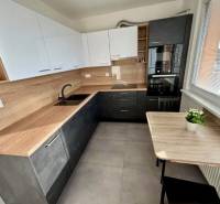 A kitchen in a 3-room apartment with light-colored furniture cabinets and a wooden decor floor.