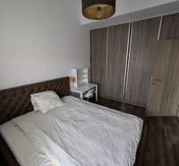 Bedroom with a bed, table, and wardrobe, 2-room apartment, floor with wood decor.