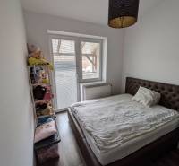Bedroom in a 2-room apartment with a bed, shelf, and wooden decor flooring.