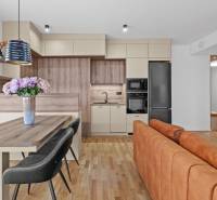 A kitchen in a 3-room apartment with a wood-patterned floor and a dining table with flowers.