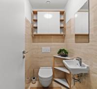 A bathroom in a 3-room apartment with beige tiles, a sink, and a toilet.