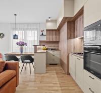 A kitchen in a 3-room apartment with a sofa, dining table, and wooden decor flooring.