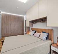 A bedroom in a 3-room apartment with a bed, pillows, built-in wardrobes, and a floor with a wooden decor.