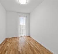 A spacious room with a wooden decor floor and a large window in a 3-room apartment.