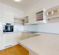 A kitchen in a 2-room apartment with a wooden decor floor and light furnishings.