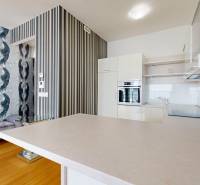 A kitchen in a 2-room apartment with a bold wallpaper and a wooden decor floor.